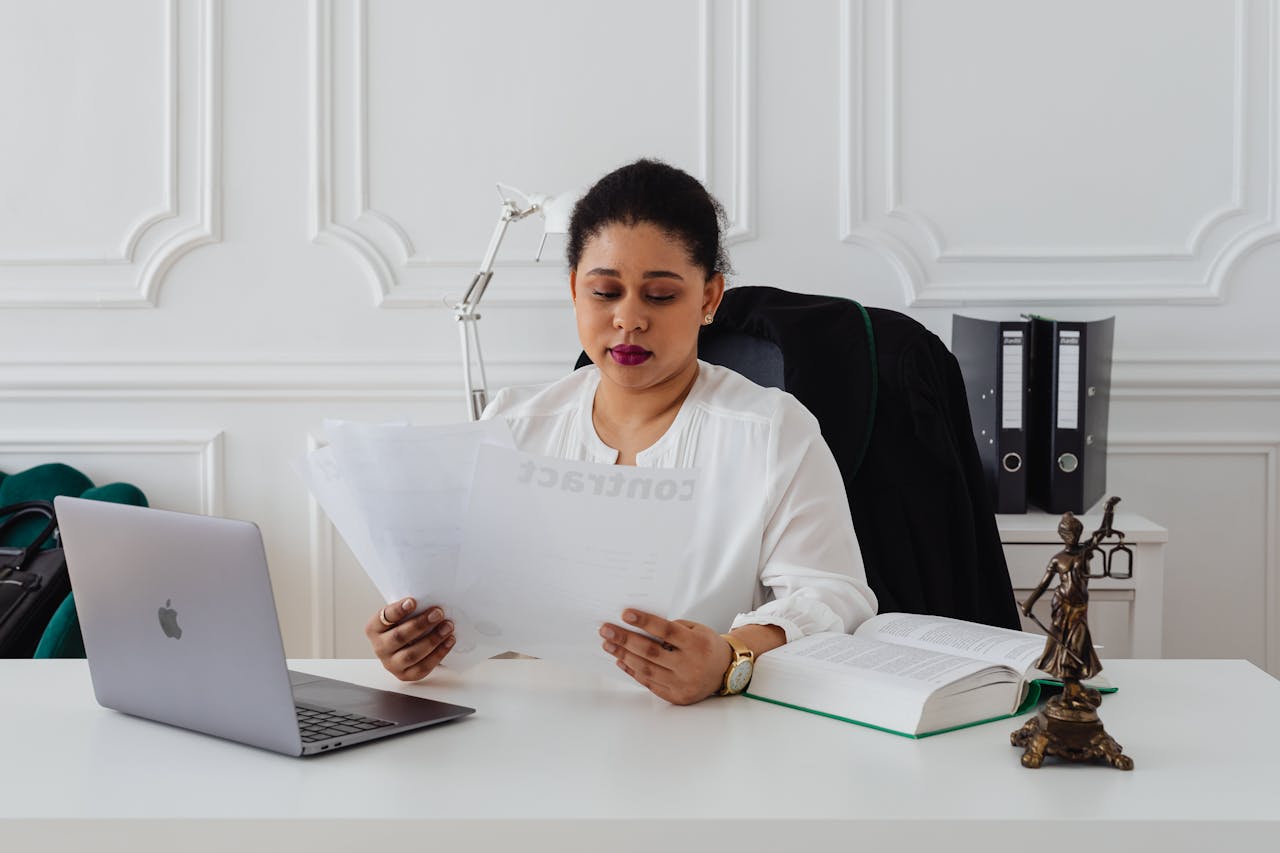 Confident businesswoman analyzing contracts at her clean, organized desk.